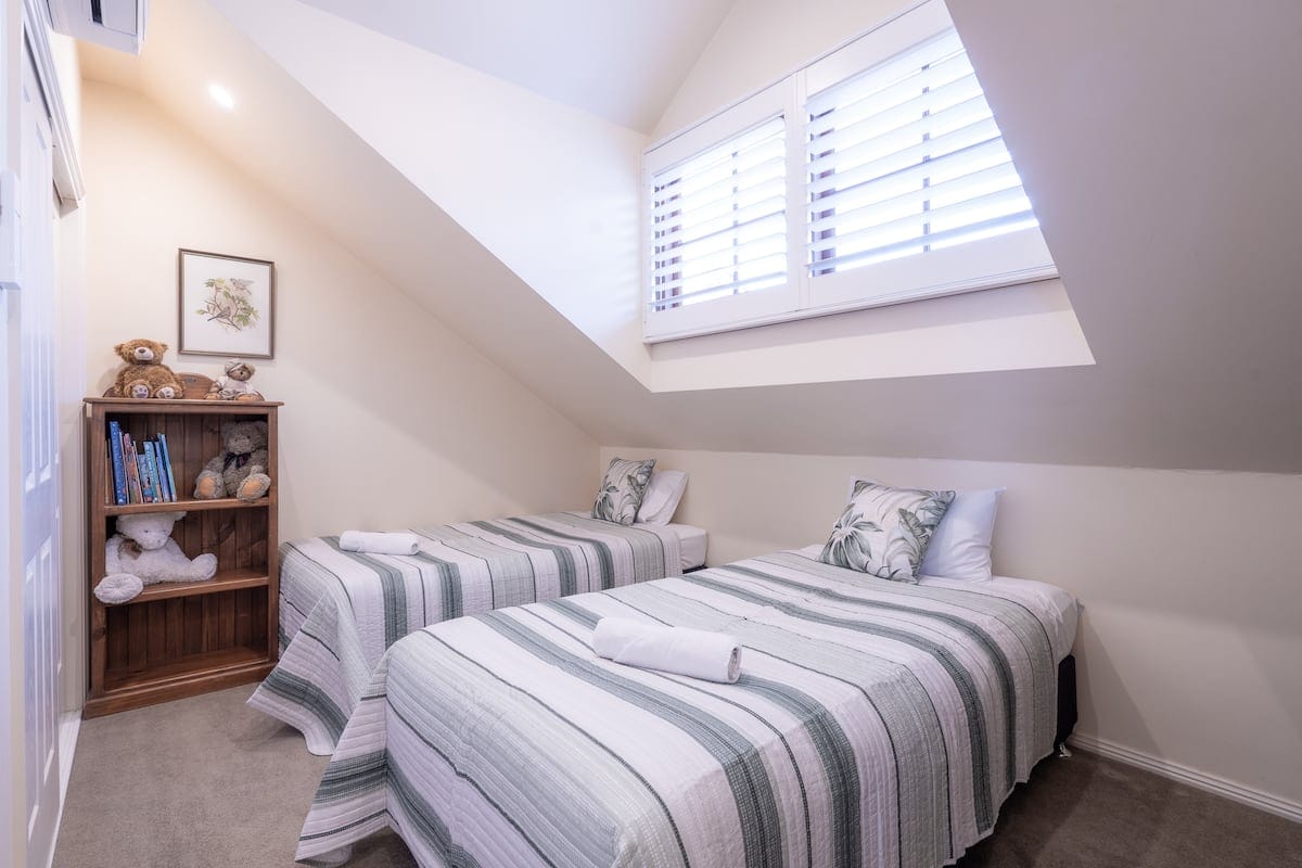 Cottage twin bedroom with pitched ceiling and bookshelf
