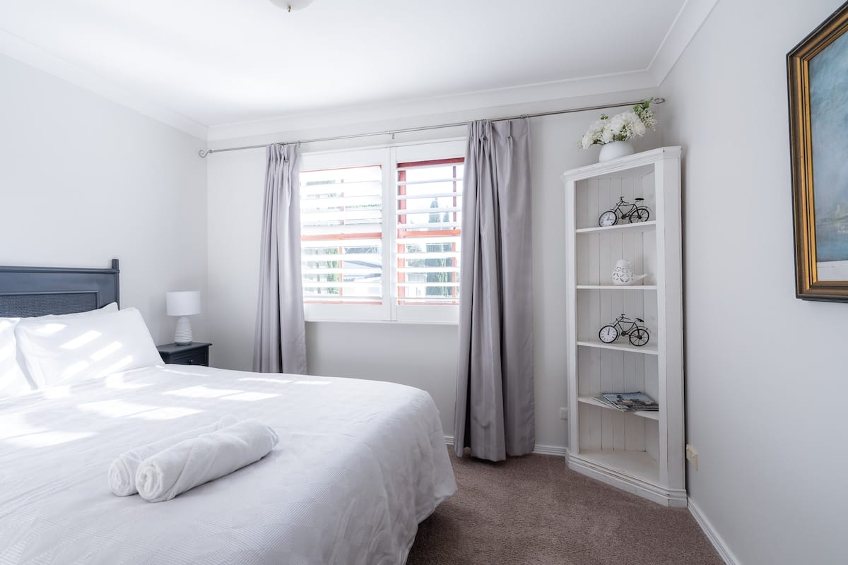 Lodge third bedroom with white linens and bookshelf