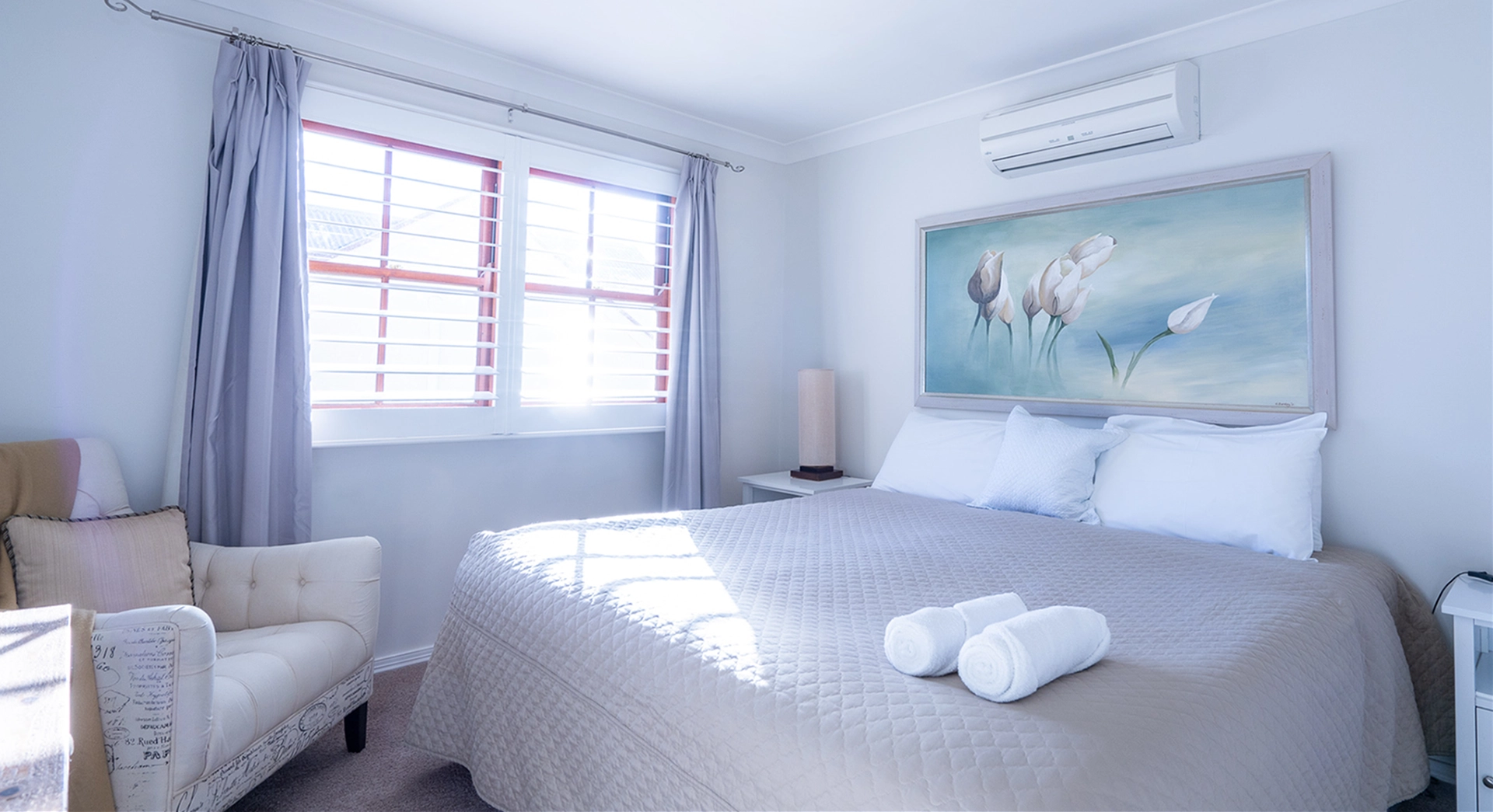 Lodge bedroom with white quilted bed and sunlit window