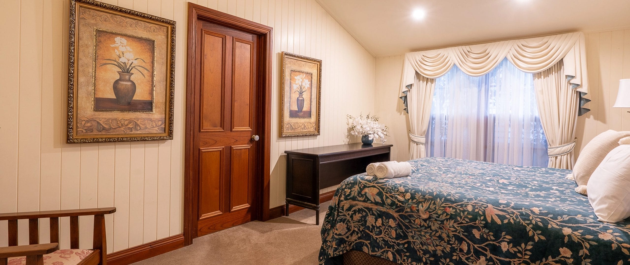 Bannockburn Cottage bedroom with framed prints, ornate curtains and dark timber doors